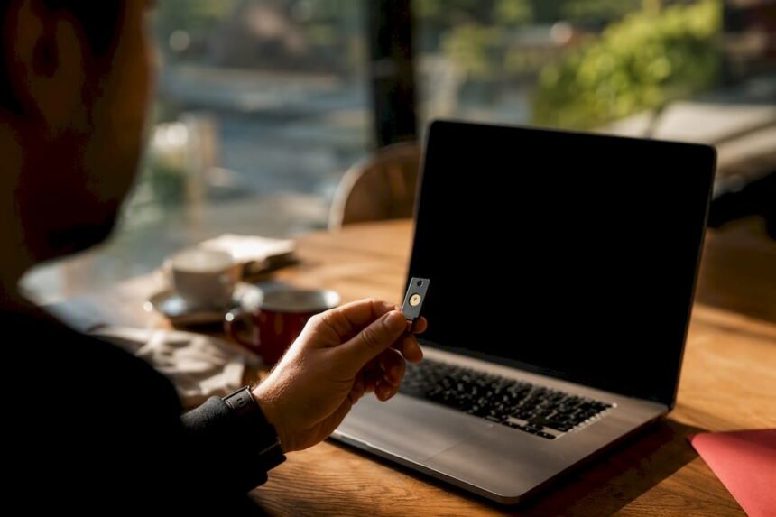 Hand holding security key near smartphone on desk