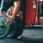 Lifter adding weight plates to a barbell for progressive overload