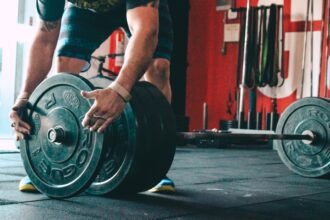 Lifter adding weight plates to a barbell for progressive overload