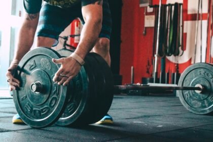 Lifter adding weight plates to a barbell for progressive overload