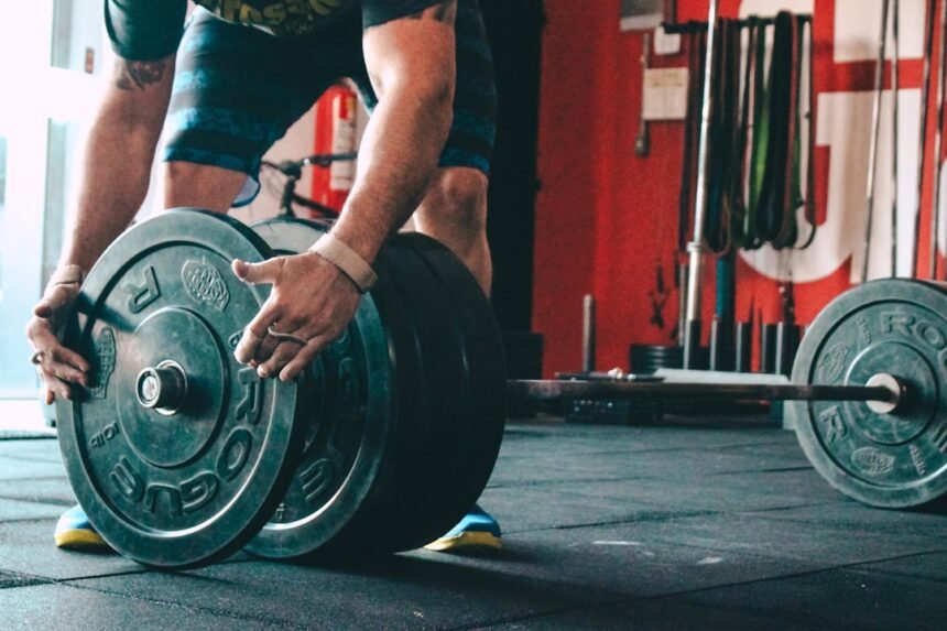 Lifter adding weight plates to a barbell for progressive overload