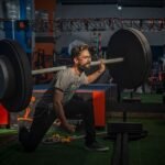 man performing barbell back squat in gym